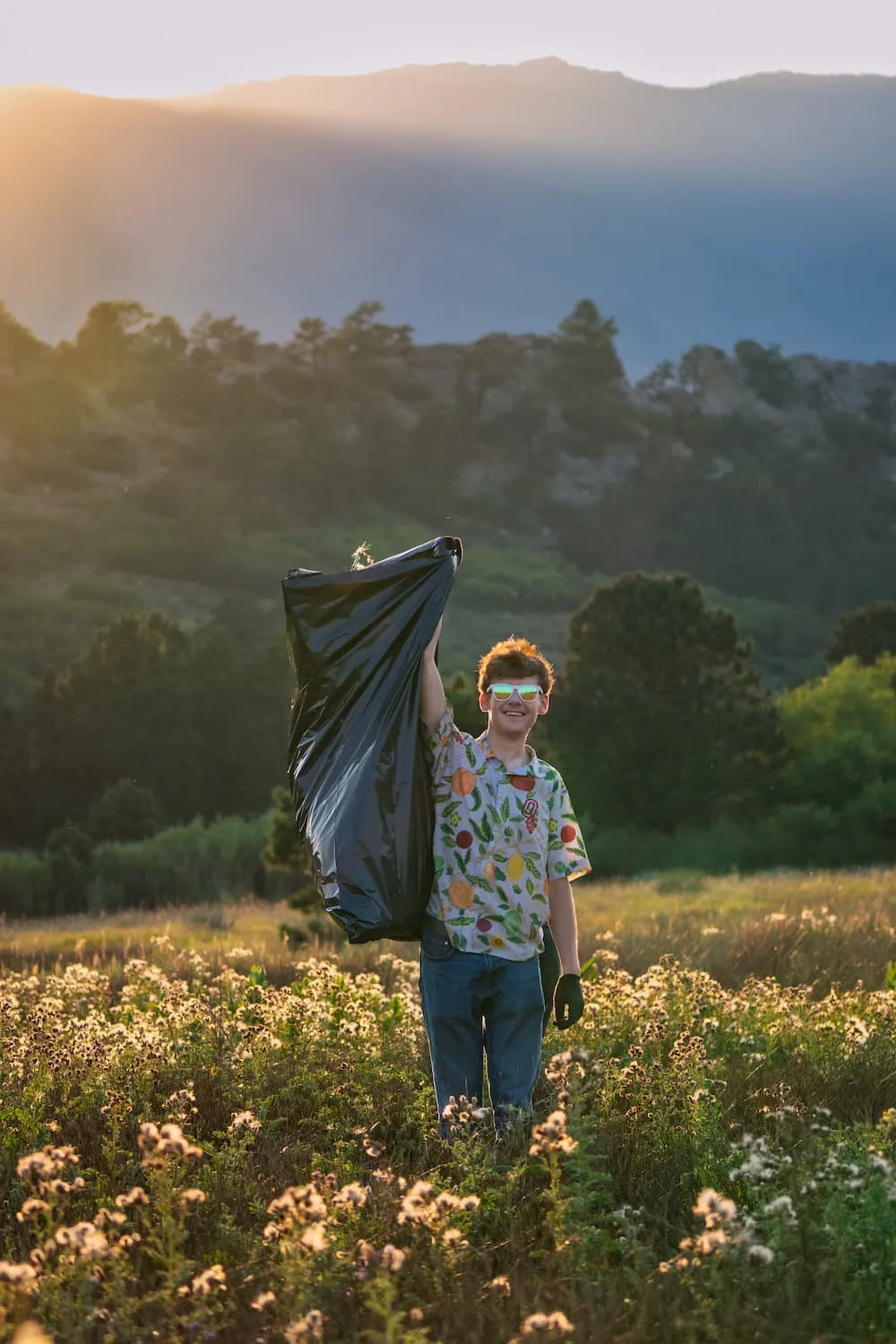 Volunteer holding a bag of collected litter in a meadow